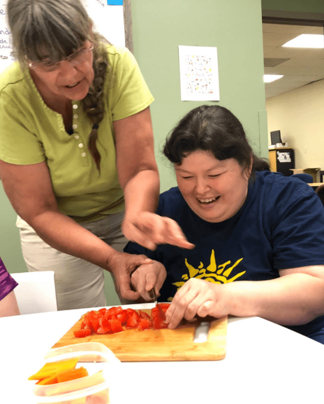 a PELS client and employee working together to chop tomatoes