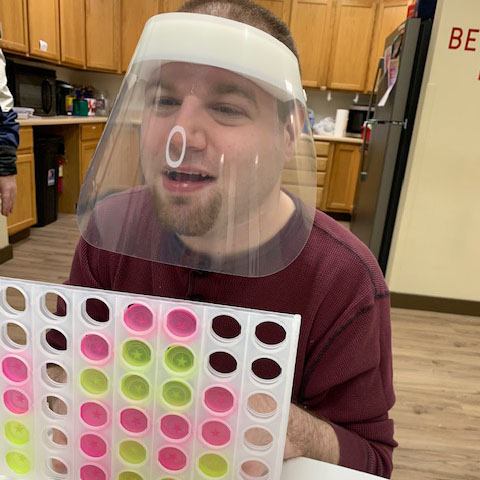 a PELS client with a face shield, playing connect four