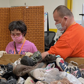 two PELS clients sorting shoes at work